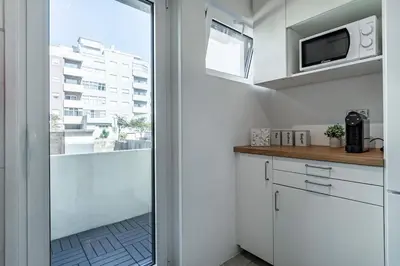 a kitchen with white cabinets and a large window at Oliveira Monteiro Flat in Porto