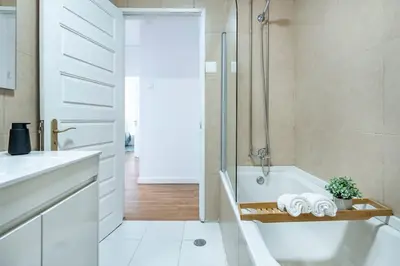 a white bathroom with a tub and a shower at Oliveira Monteiro Flat in Porto