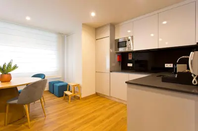 a kitchen with white cabinets and a table and chairs at Aposentus - Sofia's House in Porto