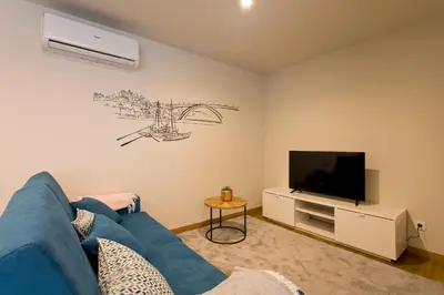 a living room with a blue couch and a tv at Aposentus - Sofia's House in Porto