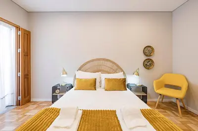 a bedroom with a large bed and a yellow chair at Lovely Flat Marquês in Porto