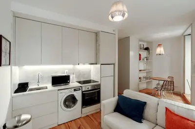 a kitchen with a washing machine and a living room at Cristelo 1 Bed next to River in Porto