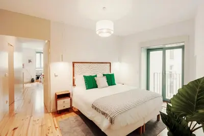 a white bedroom with a large bed with green pillows at Cristelo 1 Bed next to River in Porto