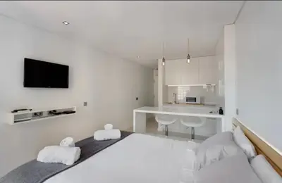 a white bedroom with a large bed and a kitchen at Cozy Studio city center in Porto