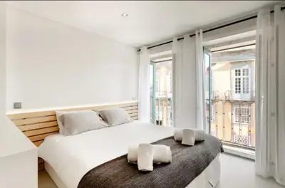 a white bedroom with a large bed with two towels on it at Cozy Studio city center in Porto