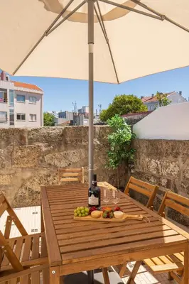 a wooden table with a bottle of wine and fruit on it at Host Wise - Elegant Colorful House w Private Terrace in Porto