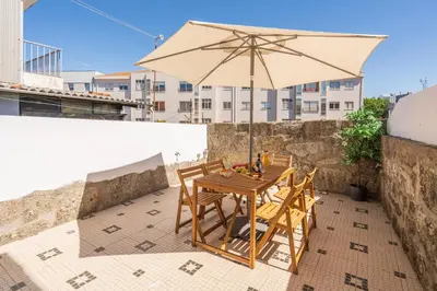 a table and chairs with an umbrella on a balcony at Host Wise - Elegant Colorful House w Private Terrace in Porto