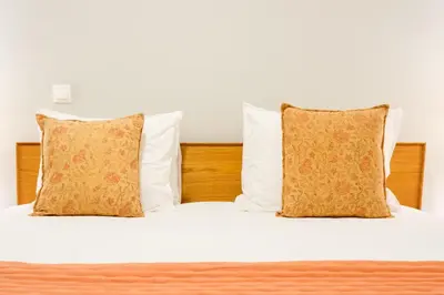 a bed with two pillows and white sheets at Alegria Colour Apartments in Porto