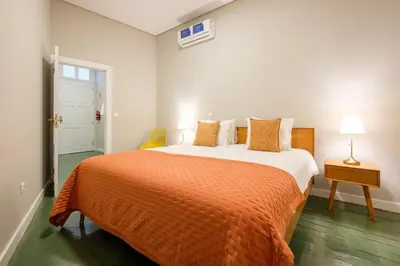 a bedroom with a large bed with an orange blanket at Alegria Colour Apartments in Porto