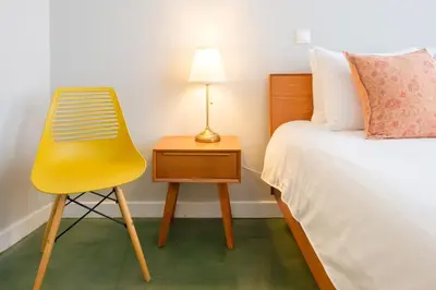 a yellow chair next to a bed and a nightstand at Alegria Colour Apartments in Porto