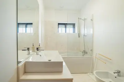 a white bathroom with a tub and a sink at City Center Grand Apartment With Seaview Terrace by Vacationy in Porto
