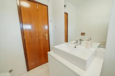 a bathroom with a white sink and a wooden door at City Center Grand Apartment With Seaview Terrace by Vacationy in Porto