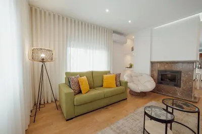 a living room with a green couch and a fireplace at City Center Grand Apartment With Seaview Terrace by Vacationy in Porto