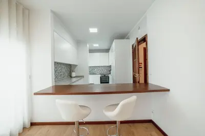 a kitchen with white cabinets and white chairs at City Center Grand Apartment With Seaview Terrace by Vacationy in Porto