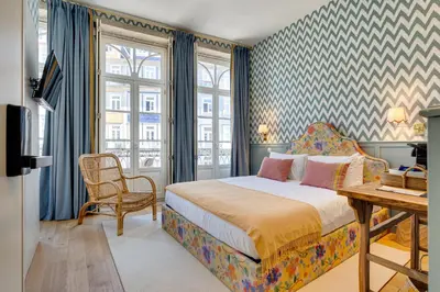 a bedroom with a bed and a desk and windows at Lóios 74 Suites by DA'HOME in Porto