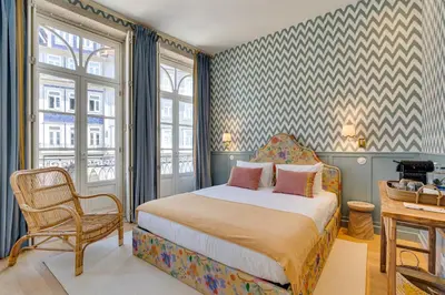 a bedroom with a bed and a chair at Lóios 74 Suites by DA'HOME in Porto