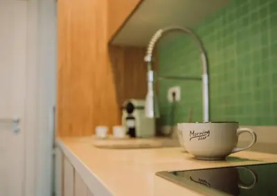 a kitchen counter with a coffee cup and a sink at D João IV Stay in Porto
