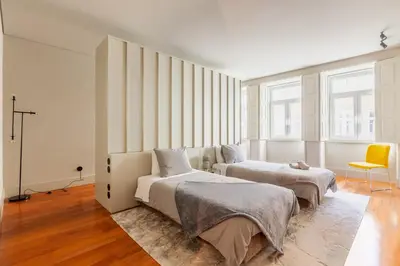 a bedroom with two beds and a yellow chair at Sta. Catarina 618 Suite in Porto