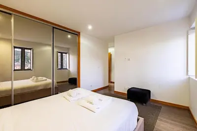 a bedroom with a large white bed and a mirror at Panoramic River View Downtown With Terrace in Porto