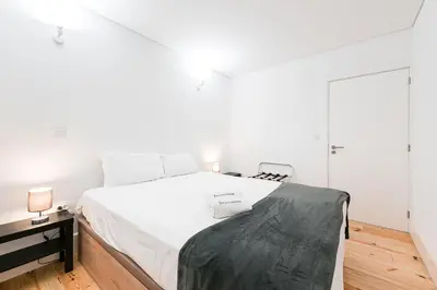 a white bedroom with a large bed and a chair at GuestReady - Arcos da Ribeira in Porto