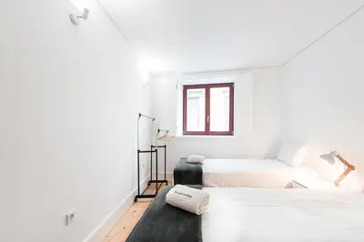 a white room with two beds and a window at GuestReady - Arcos da Ribeira in Porto