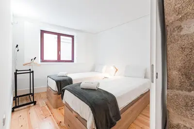 a white bedroom with two beds and a window at GuestReady - Arcos da Ribeira in Porto