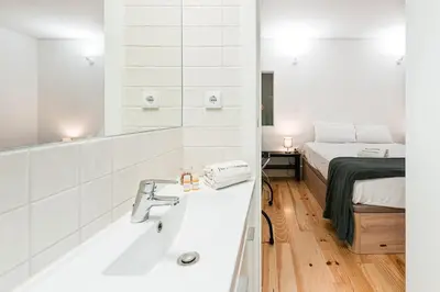 a bathroom with a sink and a bed and a mirror at GuestReady - Arcos da Ribeira in Porto