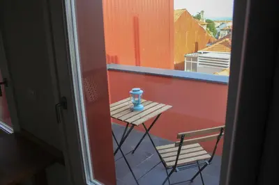 a small table and chair on a balcony with a window at Oporto Trendy Apartments in Porto