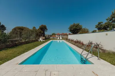 a kitchen with white cabinets and a sink and a table at Home With a Pool by Vacationy in Porto