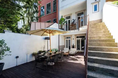 a patio with a table and an umbrella at BmyGuest Collection - The Marquis Luxury Garden Apartment in Porto