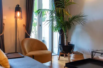 a living room with a chair and a potted plant at BmyGuest Collection - The Marquis Luxury Garden Apartment in Porto