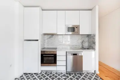 a kitchen with white cabinets and stainless steel appliances at VIVA Bonfim Cozy Home in Porto