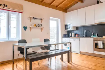 a kitchen with white cabinets and a table and chairs at Casa do Vasco in Porto