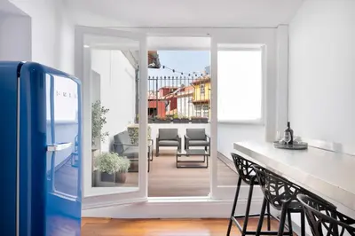 a kitchen with a door open to a balcony with chairs at Historical Penthouse at Cardosas Block in Porto