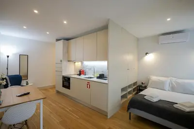 a bedroom with a bed and a desk and a kitchen at Mártires Sweet Apts by PortoCityHosts in Porto