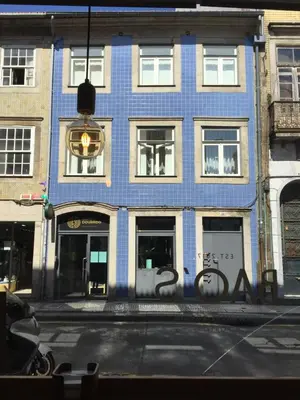 a blue building with graffiti on the side of the street at Capim Dourado Apartments Cedofeita in Porto