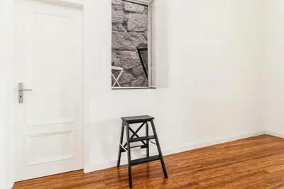 a stool in an empty room with a window at Belly Angel Apartment in Porto