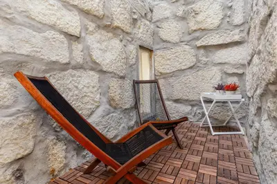 a wooden chair sitting in front of a stone wall at Belly Angel Apartment in Porto