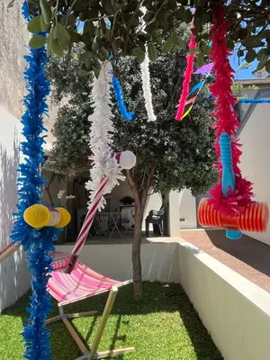 a chair under a tree in a yard with streamers at JM Alojamento local no Porto in Porto
