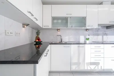 a kitchen with white cabinets and a black counter top at Host Wise - Gorgeous Spacious Flat - Ace Location in Porto
