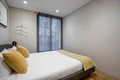 a white bedroom with a bed and a window at Primrose 1BR Delight w Parking by LovelyStay in Porto