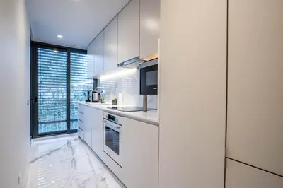 a kitchen with white cabinets and a large window at Primrose 1BR Delight w Parking by LovelyStay in Porto
