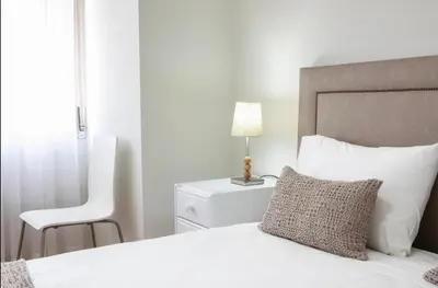 a bedroom with a white bed and a chair at Belas Artes Apartment by LovelyStay in Porto