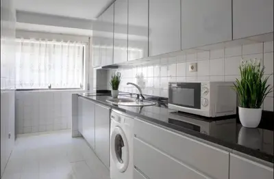 a white kitchen with a sink and a microwave at Belas Artes Apartment by LovelyStay in Porto