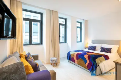a bedroom with a bed and a couch and windows at Porto Formosa Central Lofts in Porto