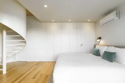 a bedroom with a white bed and a staircase at Feel Porto Corporate Housing Boavista in Porto