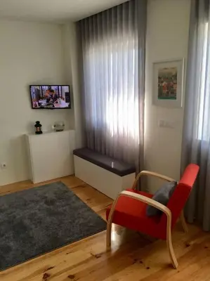 a living room with a red chair and a bench at Studio Jardim São Lázaro in Porto
