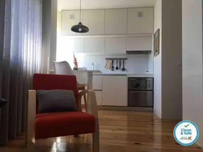 a living room with a red chair and a kitchen at Studio Jardim São Lázaro in Porto