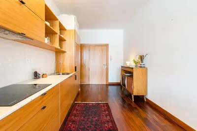 a kitchen with wooden cabinets and a red rug at Hey Apartments C in Porto