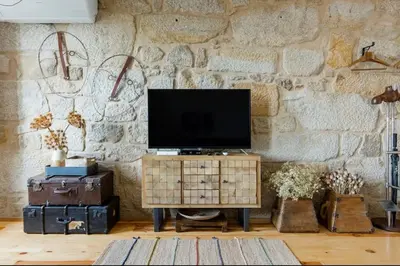 a living room with a tv on a stone wall at 1892 - Ribeira Loft in Porto